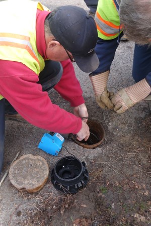 Two men placing monitoring equipment into water pipe